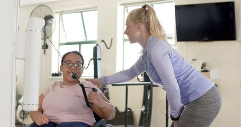 Therapist assisting woman in physical rehabilitation with equipment