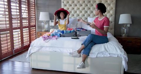 Female Couple Packing Suitcase at Home and Planning Vacation
