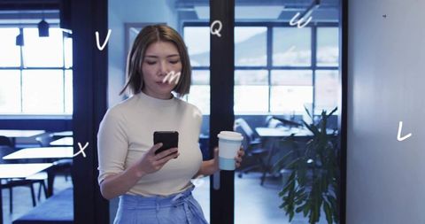 Young professional holding coffee and checking smartphone in modern coworking space