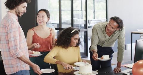 Diverse colleagues celebrating with birthday cake in modern office