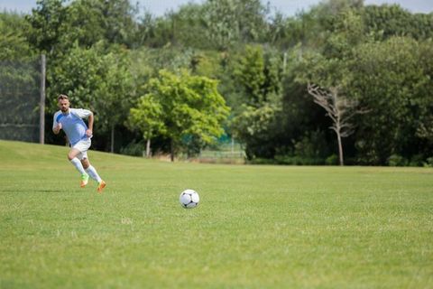 Male Soccer Player Running Across Open Field in Active Play