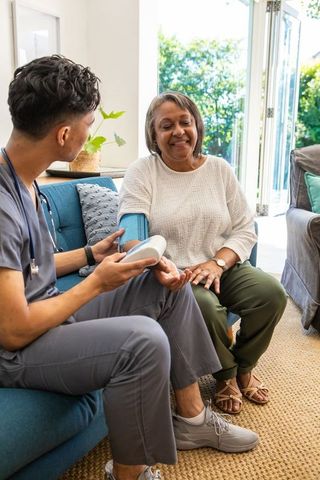 Nurse and senior woman using blood pressure monitor at home
