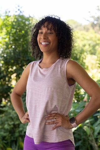Smiling african american woman wearing smartwatch in activewear, outdoor wellness garden