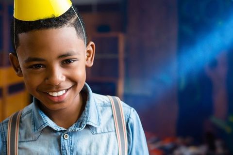 Smiling Boy Celebrating in Playroom with Party Hat