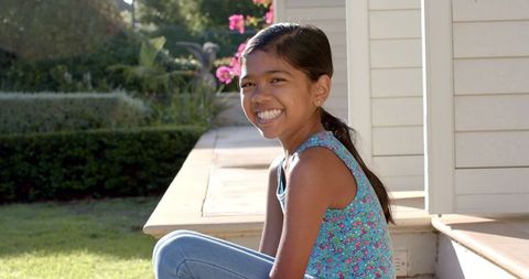 Smiling Young Girl Enjoying Sunny Day Outdoors on Porch