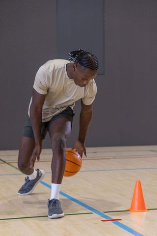 Basketball player dribbling between cones on indoor hardwood court during training session