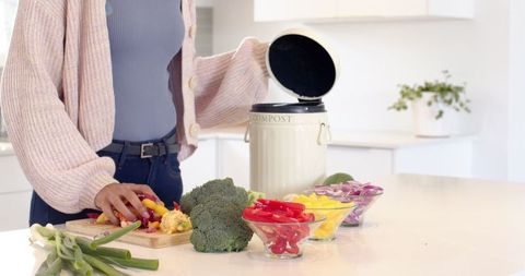 Woman Preparing Vegetables in Eco-Friendly Kitchen with Compost Bin