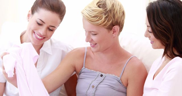 Three Women Smiling and Looking at Baby Clothes - Download Free Stock Images Pikwizard.com