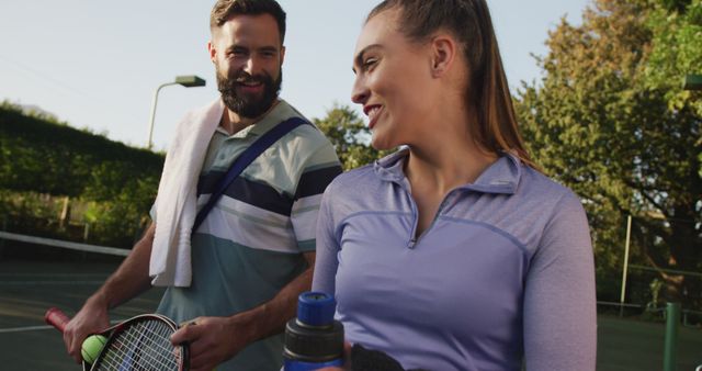 Two tennis players are smiling and conversing after a match. This can be used to promote sportsmanship, outdoor recreational activities, and healthy lifestyle concepts for advertising or blogs.