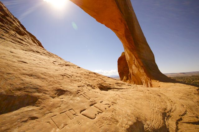 Sunlit Natural Rock Arch in Desert with Carvings - Download Free Stock Photos Pikwizard.com