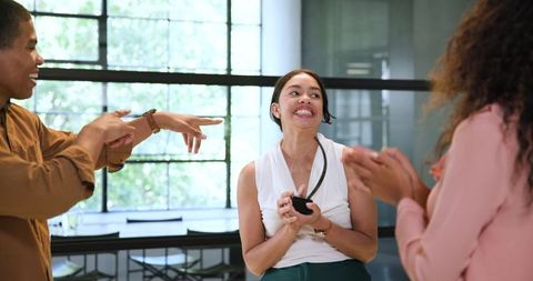 Excited colleagues celebrate employee achievement in modern office