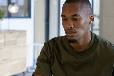 Contemplative african american man working from home in modern light-filled workspace