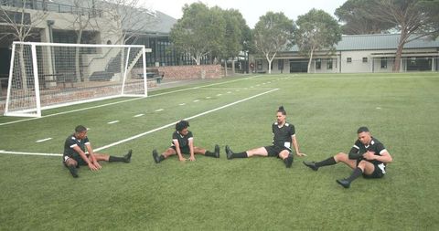 Soccer Players Stretching on Field Before Practice Session