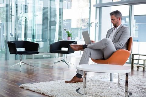 Business Executive in Modern Lounge Working on Laptop