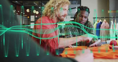 Fashion designers collaborating over tablet and orange garment with digital waveform overlay