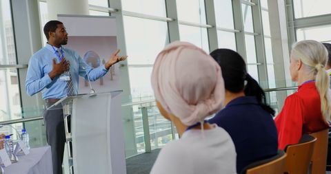 a professional speaker engages with an audience at a business seminar, ideal for showcasing diverse speakers or public speaking events. potential use includes business conference promotions, speaker brochures, and diversity in business initiatives.