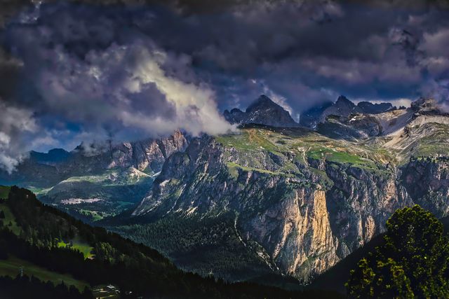 Depicts a dramatic mountain range under a stormy sky with dark clouds, showcasing nature and wilderness. Ideal for backgrounds, travel blogs, nature magazines, and environmental awareness campaigns.