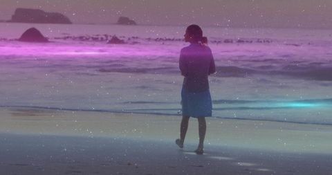 Woman contemplating ocean at dusk amidst serene lights