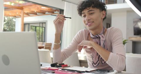 Man practicing makeup techniques using laptop and ring light at home