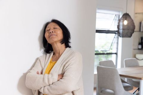 Senior woman relaxing against wall in modern interior space