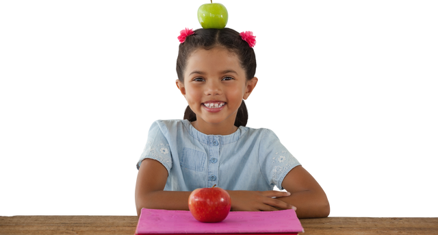 Smiling Girl Balancing Green Apple on Head with Red Apple on Desk - Download Free Stock Videos Pikwizard.com