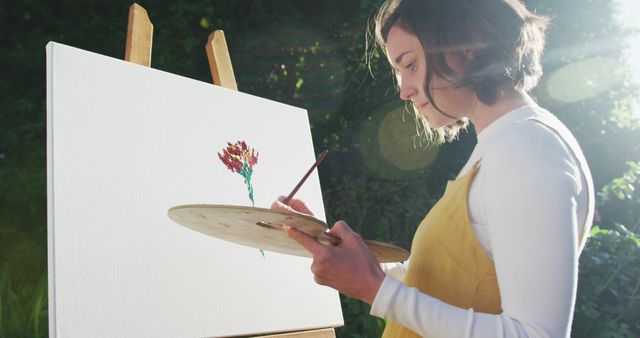 Caucasian woman with brown hair painting in sunny garden - Download Free Stock Photos Pikwizard.com