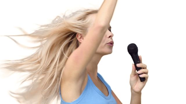 Woman pointing while singing with a microphone against a white background