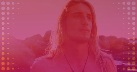 Peaceful man with long hair standing on rocky seashore