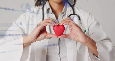 Mid-adult doctor holding red heart raising heart health awareness and preventive care messaging