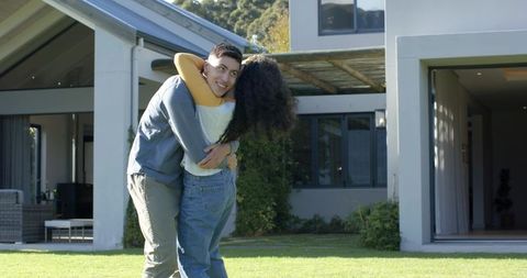 Couple Embracing on Lawn in Front of Modern Suburban Home