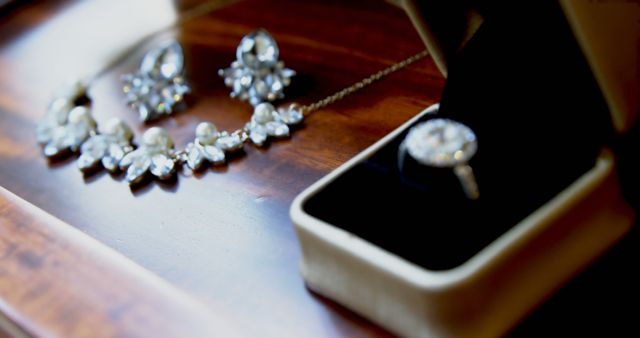 Close-up of a beautiful bridal jewelry set with a necklace, earrings, and a diamond ring displayed on a wooden surface. This image highlights the luxurious and elegant nature of these accessories, perfect for use in wedding planning materials, jewelry advertisements, bridal magazines, and luxury lifestyle blogs.