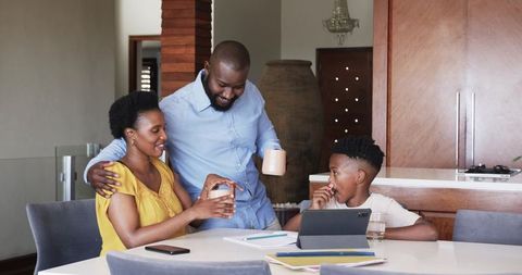 African American family enjoying morning together at kitchen table with tablet and coffee
