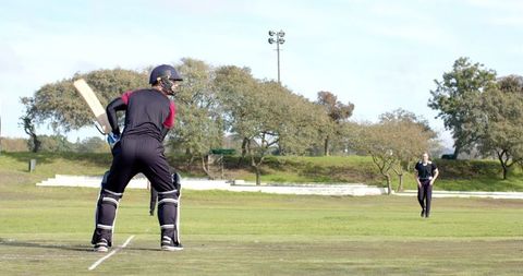 Cricketer preparing to bat on outdoor field