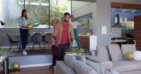 Group preparing modern open-plan living room for casual celebration walking with balloons