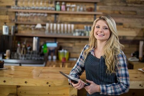 Friendly Barista Holding Tablet in Rustic Cafe