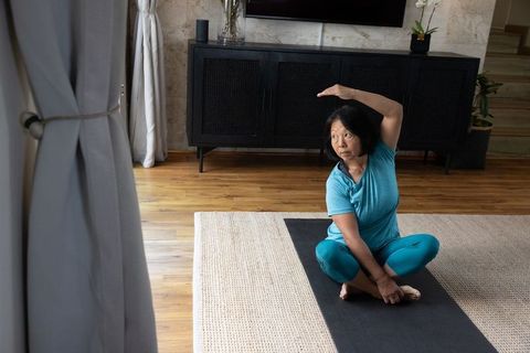 Senior Asian Woman Practicing Yoga Pose in Comfortable Home