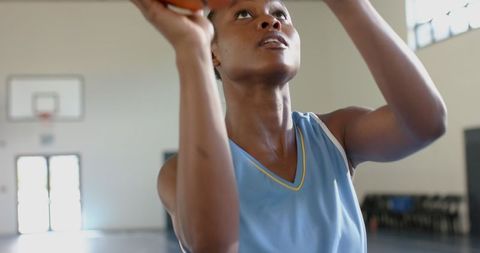 Focused female athlete preparing to shoot basketball indoors