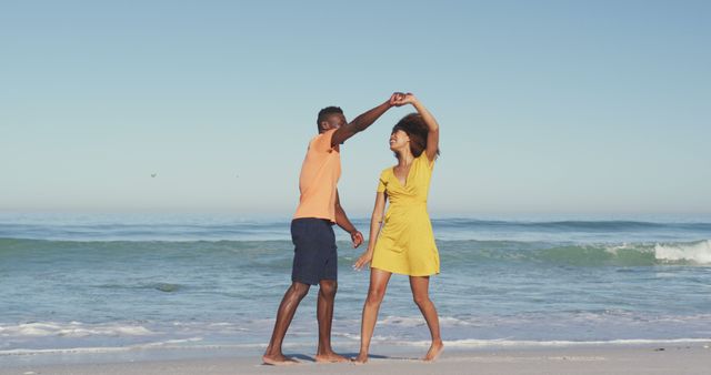 Couple dancing barefoot on sandy beach by the ocean at sunrise. Perfect for travel ads, romantic getaways, vacation brochures, beach-centric lifestyle campaigns, and summer promotional materials.