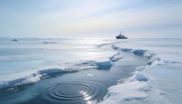 Polar ice channel cutting through frozen sea with research ship on horizon, rippling lead