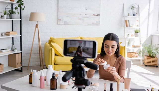 Filming beauty creator demonstrating skincare cream routine in bright modern home studio