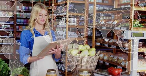 Shop worker checking inventory at organic grocery with world map overlay