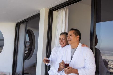 Relaxed Senior Couple in Bathrobes Enjoying Balcony View