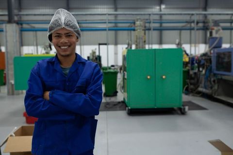 Smiling Factory Worker in Blue Coverall on Spacious Manufacturing Floor