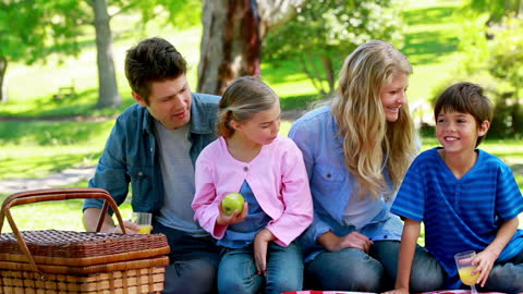 Happy Family Enjoying Picnic in Lush Parkland Setting