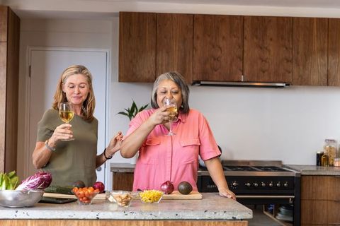 Senior Women Toasting with White Wine in Modern Kitchen