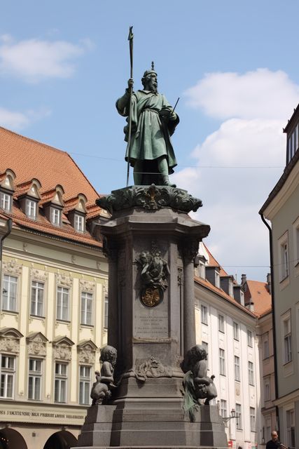 Historical statue in medieval European town square. Ancient monument in city center surrounded by classical buildings. Ideal for concepts of history, sightseeing, cultural heritage, tourism, and European architecture. Perfect for travel blogs, historical articles, and cultural preservation themes.