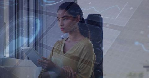 Businesswoman holding tablet analyzing holographic graphs