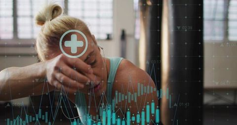 Woman pausing workout wiping sweat with forearm while monitoring fitness data overlay