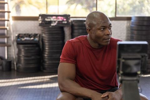 African american athlete resting on rowing machine in gym after intense workout recovering