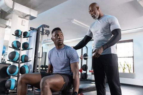 Trainer correcting bench press form while coaching client during strength training session